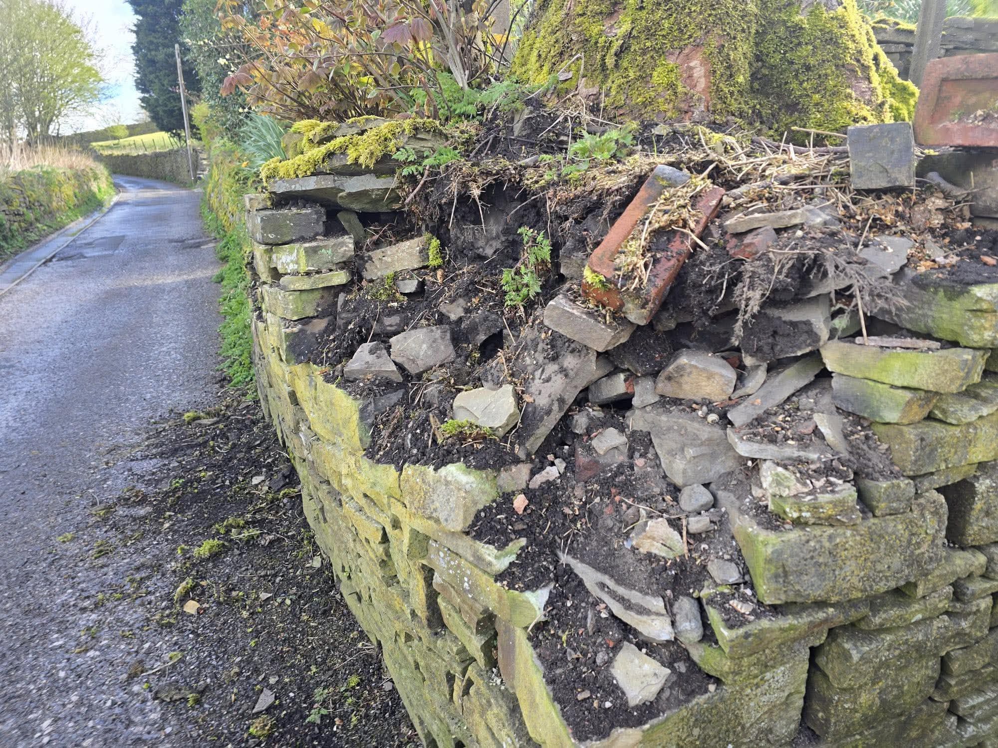 Dry stone wall along a roadside knocked down by a vehicle impact
