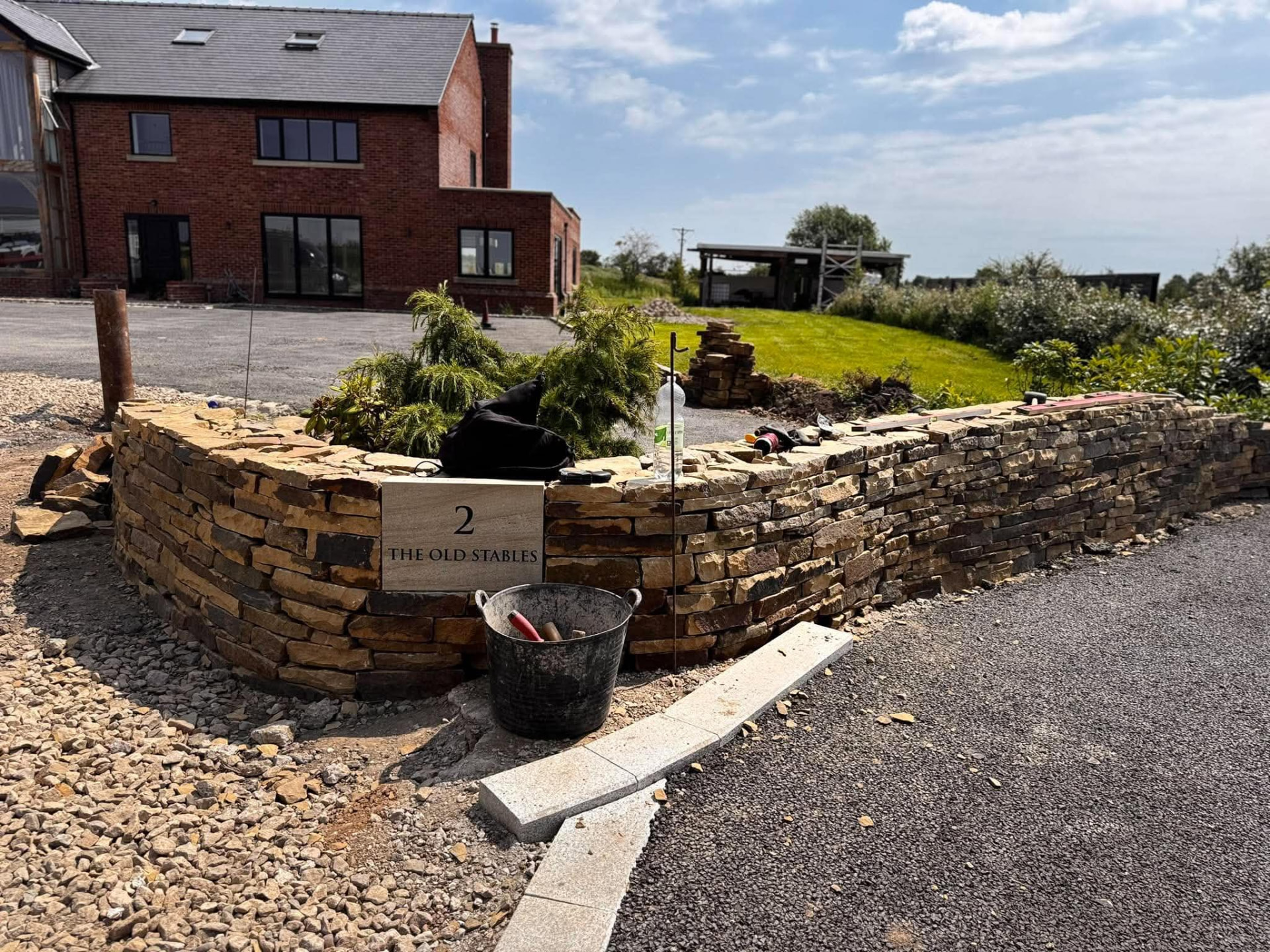 Coursed natural stone wall with an integrated stone plaque at a driveway entrance